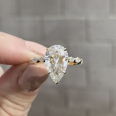 a person holding an engagement ring with a diamond in it's center and side stones on the band