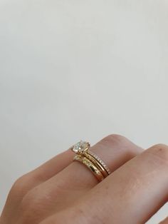 a woman's hand with two gold rings on her fingers and one diamond ring in the middle