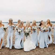 a group of women standing on top of a beach next to each other holding bouquets