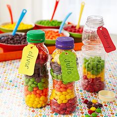 colorful candies in glass jars with name tags on them and labels attached to the bottles