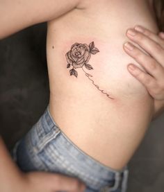 a woman's stomach with a rose tattoo on her left side ribcage