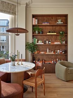 a living room filled with furniture next to a large open book shelf on top of a hard wood floor