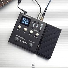 an electronic device is sitting on top of a metal surface with a guitar in the background