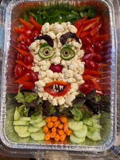 a plastic container filled with lots of vegetables and face made out of cauliflower