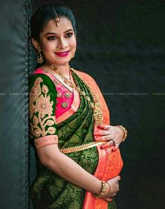 a woman in an orange and green sari posing for the camera with her hands on her hips