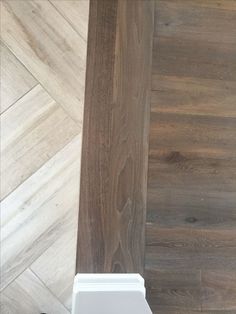 a white toilet sitting on top of a wooden floor next to a tiled bathroom wall