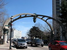 cars driving under an arch on a city street