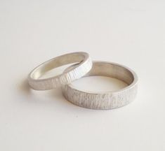 two wedding rings sitting next to each other on top of a white surface with no one in it