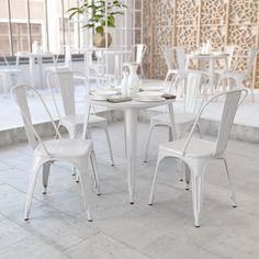 a white table and chairs in a room with tile flooring on the ground, next to a potted plant