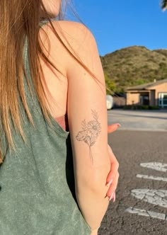 a woman with a flower tattoo on her arm is walking down the street in front of a house