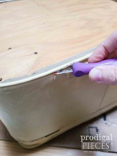 someone is using a purple plastic tool to trim the bottom of a suitcase