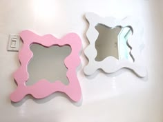 two white and pink mirrors on the wall