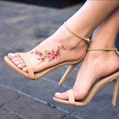 a woman's feet with pink flowers on the side and ankle tattoos in front