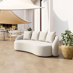 a white couch sitting on top of a tiled floor next to a table and chairs