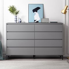 a gray dresser with an umbrella painting on the top and a lamp next to it