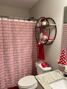 a bathroom decorated for christmas with red and white decor on the shower curtain, toilet seat cover and sink