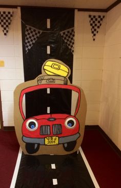 a red car with luggage on top is parked in front of a black and white wall