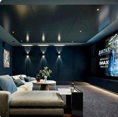 a home theater with couches and a table in front of a large screen on the wall