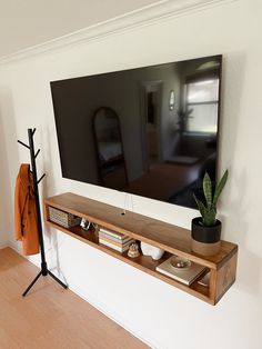 a flat screen tv mounted to the side of a wall next to a potted plant