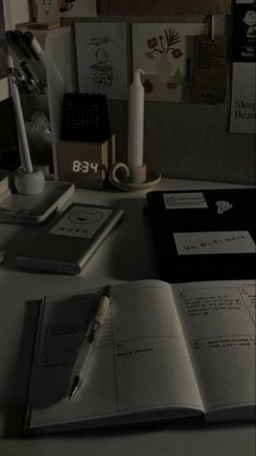 an open book sitting on top of a desk next to a pen and paper holder