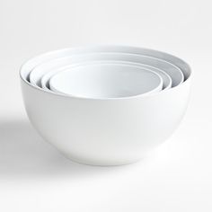 a stack of white bowls sitting next to each other on top of a white table