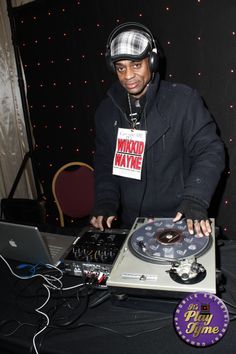 a man with headphones on standing in front of a dj's turntable