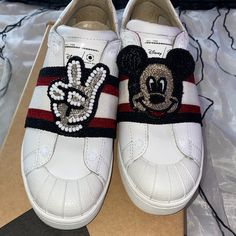 a pair of white shoes with mickey mouse embellishments on the front and side