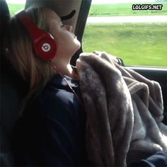 a woman wearing headphones sitting in the back seat of a car