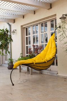 a yellow hammock sitting on top of a tiled floor next to potted plants