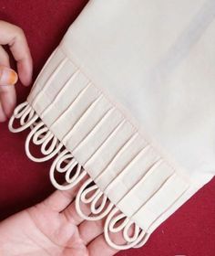 a person is sewing on the back of a white dress with an orange ring at the end