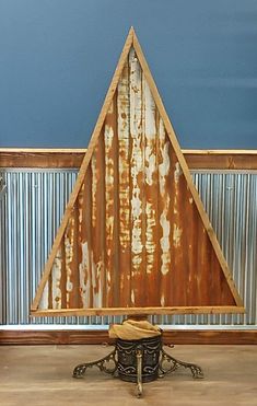 a chair sitting in front of a metal wall with a triangle shaped design on it