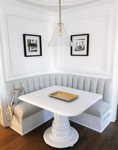 a white table and bench in a room with framed pictures on the wall behind it