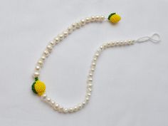 a beaded necklace with pineapples and pearls is shown on a white background