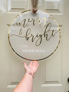 a hand holding up a sign that says merry and bright the hennings on it