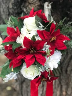 a bridal bouquet with red and white flowers on the side of a tree trunk