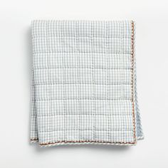 a blue and white checkered blanket on a white tablecloth with brown piping