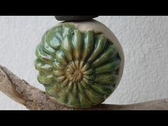 a green vase sitting on top of a wooden branch