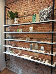 the shelves are filled with glasses and other items on display in front of a brick wall