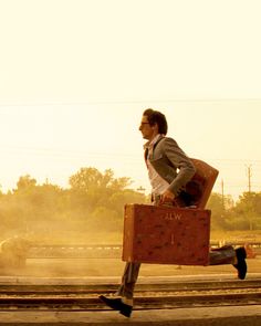 a man running down the street with a suitcase in his hand and an elephant behind him