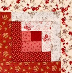 a red and white patchwork quilt with flowers on the border, in front of a flowered background