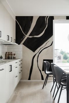 a dining room table and chairs in front of a large painting on the wall behind it