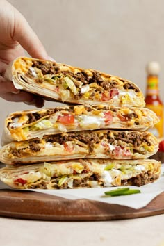 a person is holding up some tacos with meat and cheese on them, along with condiments