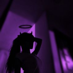 a woman with long hair standing in front of a purple light and holding her head