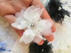 a person is holding two flower clips in their hand, both with pearls on them