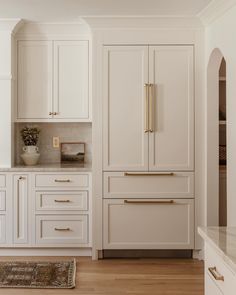 a kitchen with white cabinets and gold handles on the doors, counter tops and drawers