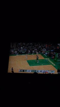 a basketball game is being played on a large screen in the middle of an arena