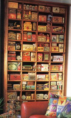 a living room filled with lots of books on top of a wooden book shelf next to a red chair