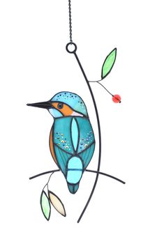 a stained glass bird on a branch with leaves and berries hanging from it's side