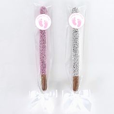 two pink and white toothbrushes wrapped in plastic with baby feet on it's side