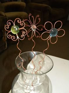 a glass vase filled with metal wire and flowers